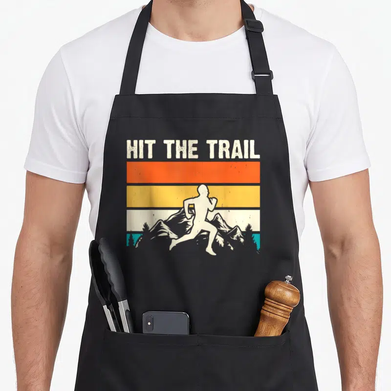 Tablier de cuisine noir avec illustration vintage d'un coureur sur fond de montagnes et bandes colorées.