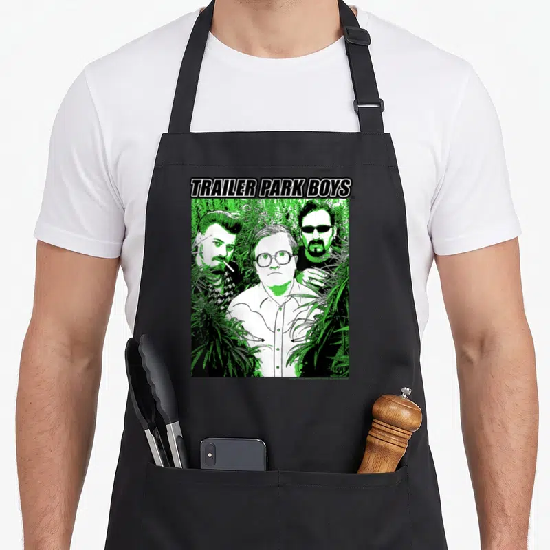 Tablier de cuisine noir avec illustration verte et noire des Trailer Park Boys In the Weeds entourés de feuilles.