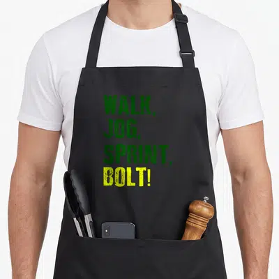 Tablier de cuisine noir avec le texte vert et jaune « WALK, JOG, SPRINT, BOLT! » imprimé au centre.