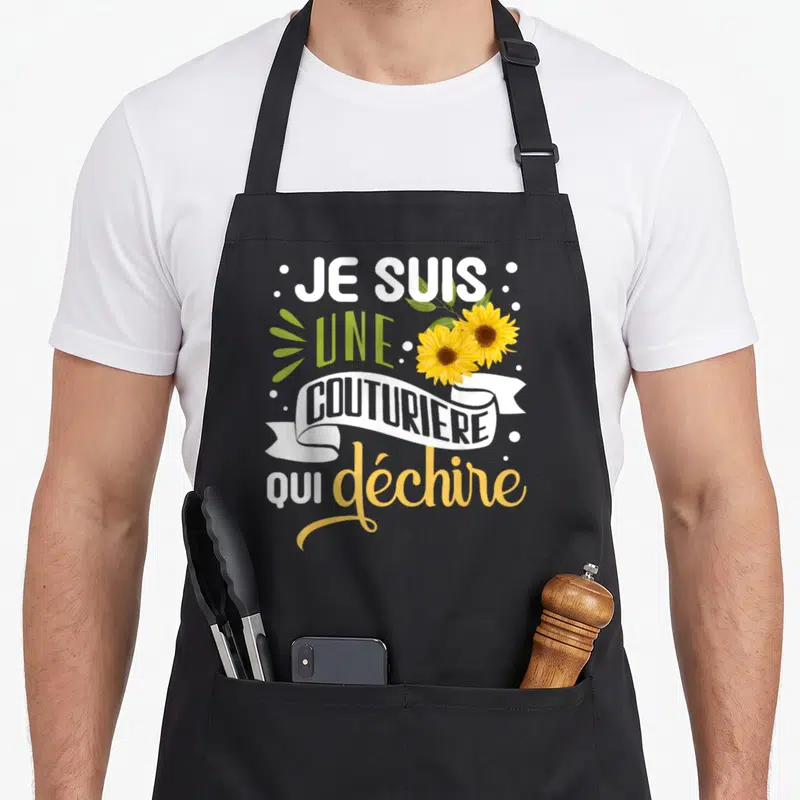 Tablier de cuisine noir avec l'inscription Je suis une couturière qui déchire et deux tournesols jaunes.