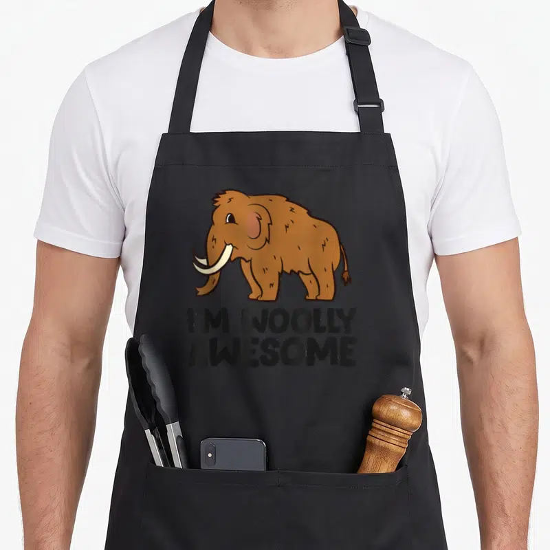 Tablier de cuisine noir avec illustration d'un mammouth brun et le texte I'M WOOLLY GÉNIAL imprimé en dessous.