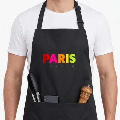 Tablier de cuisine noir avec l'inscription PARIS en lettres multicolores et FRANCE en blanc sous le mot principal.