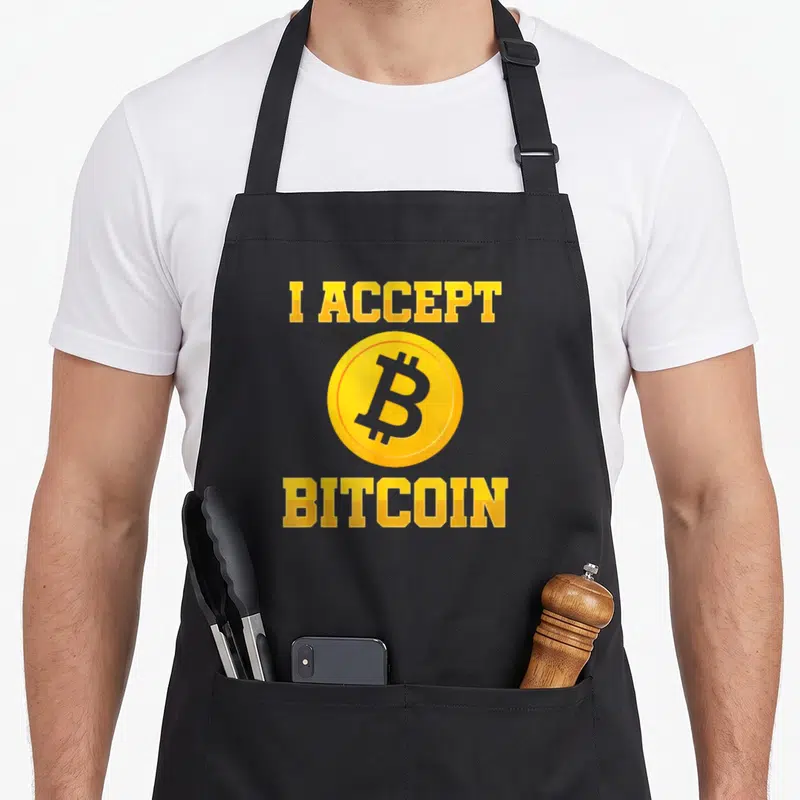 Tablier de cuisine noir avec inscription jaune I Accept Bitcoin et logo BTC doré central.