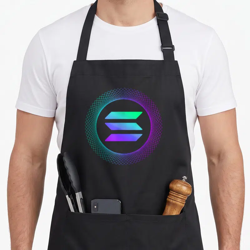 Tablier de cuisine noir avec logo Solana crypto aux couleurs vives et motif géométrique circulaire autour des barnes horizontales.