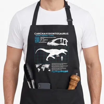 Tablier de cuisine noir avec une fiche technique blanche et bleue illustrant un Carcharodontosaurus et son squelette crânien.