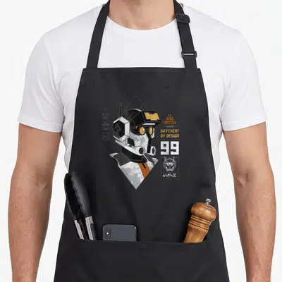 Tablier de cuisine noir avec illustration du casque Tech et le texte Different by Design 99.