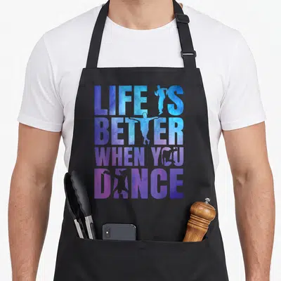 Tablier de cuisine noir avec inscription Life is better when you dance et silhouettes de danseurs en dégradé bleu et violet.