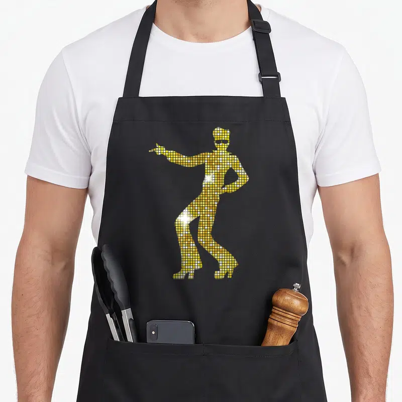 Tablier de cuisine noir avec une silhouette de danseur disco formée de carrés dorés et argentés imitant un miroir.