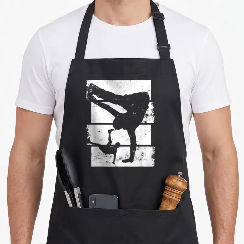 Tablier de cuisine noir avec silhouette grise d'un danseur de break en position acrobatique sur fond texturé blanc.