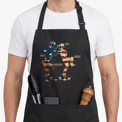 Tablier de cuisine noir avec deux silhouettes dansant en motif drapeau américain et les mots FIVE SIX SEVEN EIGHT.