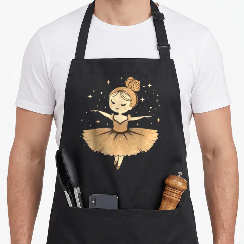 Tablier de cuisine noir avec illustration d'une ballerine en tutu doré, les bras ouverts et des étoiles autour du visage souriant.