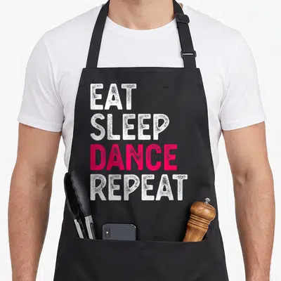 Tablier de cuisine noir avec le texte Eat Sleep Dance Repeat en lettres blanches et roses vives sur fond uni.
