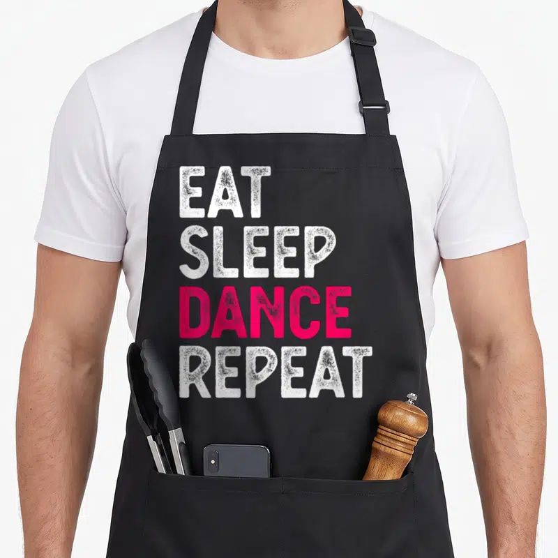 Tablier de cuisine noir avec le texte Eat Sleep Dance Repeat en lettres blanches et roses vives sur fond uni.