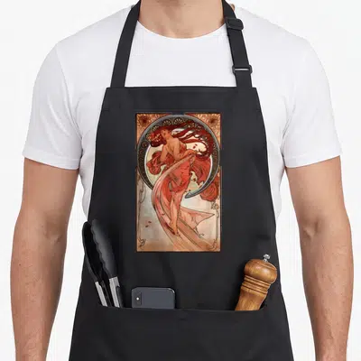Tablier de cuisine noir avec une illustration Art Nouveau représentant une danseuse aux cheveux roux et des drapés fluides.