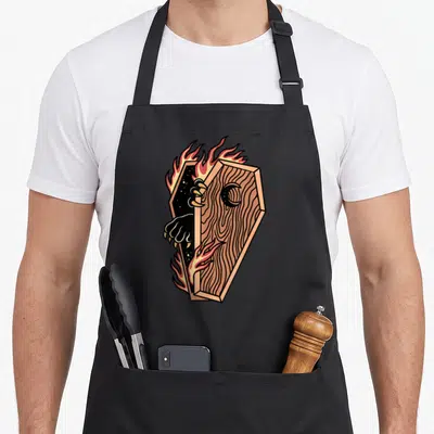 Tablier de cuisine noir avec illustration d'un cercueil enflammé aux griffes noires sortant de l'ombre.