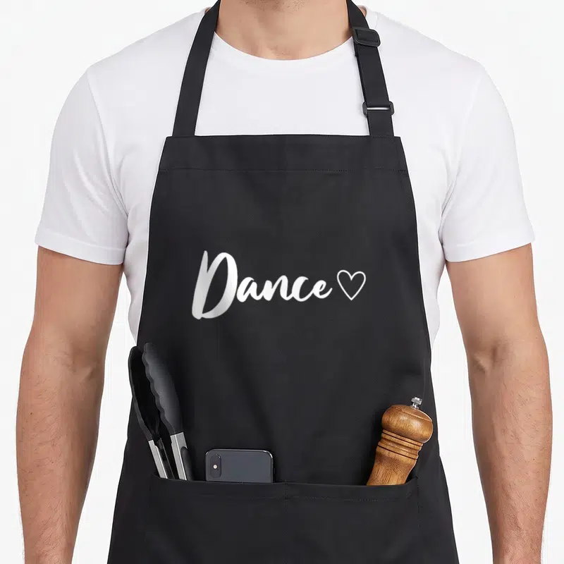 Tablier de cuisine noir avec inscription blanche Dance suivie d'un petit cœur stylisé.