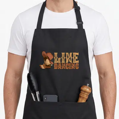 Tablier de cuisine noir avec illustration de bottes, chapeau cowboy et texte Line Dancing orange