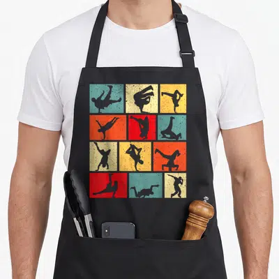 Tablier de cuisine noir avec grille de douze carrés colorés affichant des silhouettes grises de breakers en acrobaties.