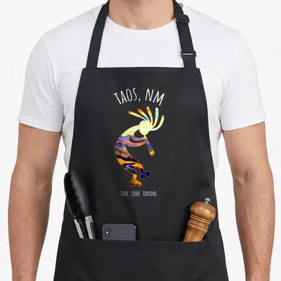 Tablier de cuisine noir avec illustration colorée d'un Kokopelli et l'inscription Taos NM Live Love Explore.