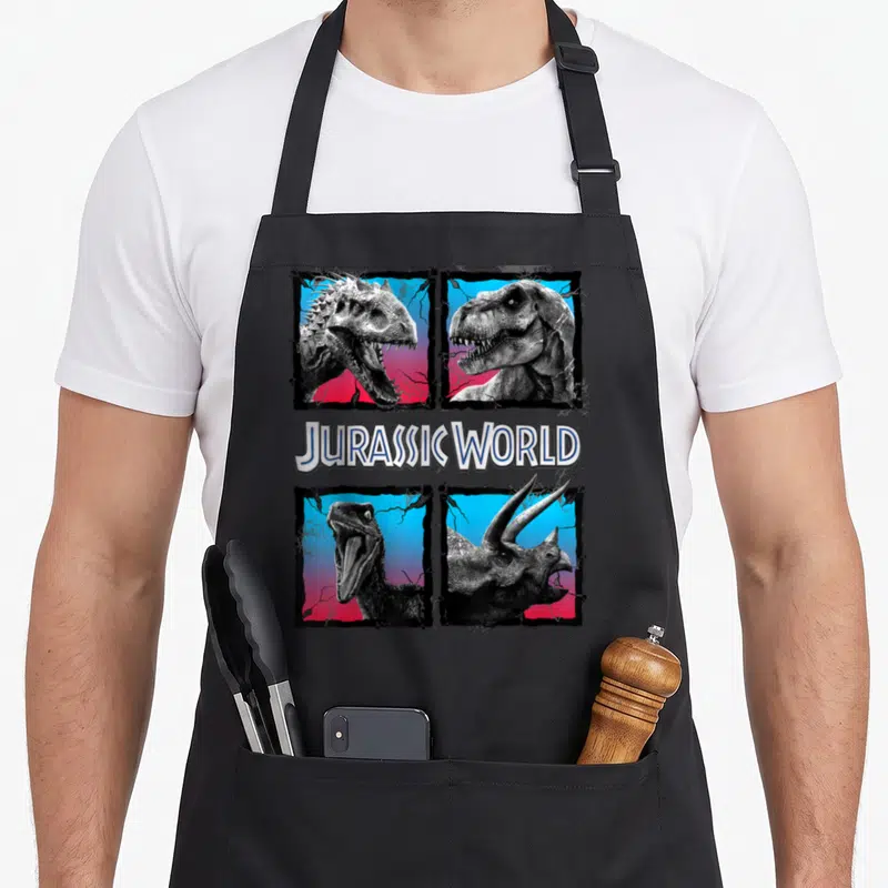 Tablier de cuisine noir avec quatre encadrés de dinosaures en noir et blanc sur fond dégradé rose et bleu.