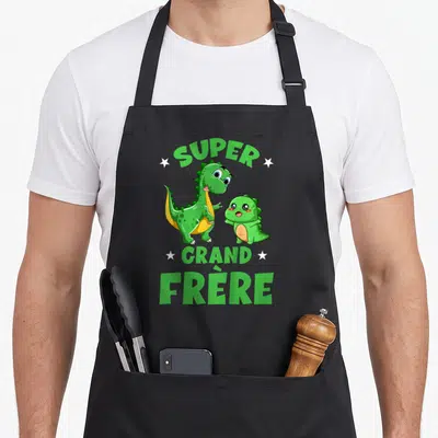 Tablier de cuisine noir avec deux dinosaures verts mignons et l'inscription super grand frère entourée d'étoiles blanches.