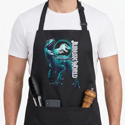 Tablier de cuisine noir avec illustration d'un raptor bleu turquoise et texte vertical Jurassic World blanc.