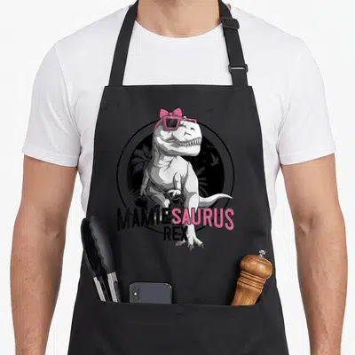 Tablier de cuisine noir avec illustration d'un dinosaure T-Rex portant des lunettes roses et un nœud papillon rose vif.