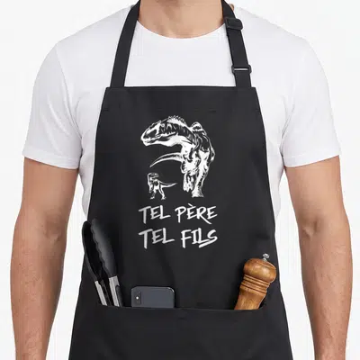 Tablier de cuisine noir avec illustration blanche d'un grand et d'un petit dinosaure sous le texte Tel Père Tel Fils.