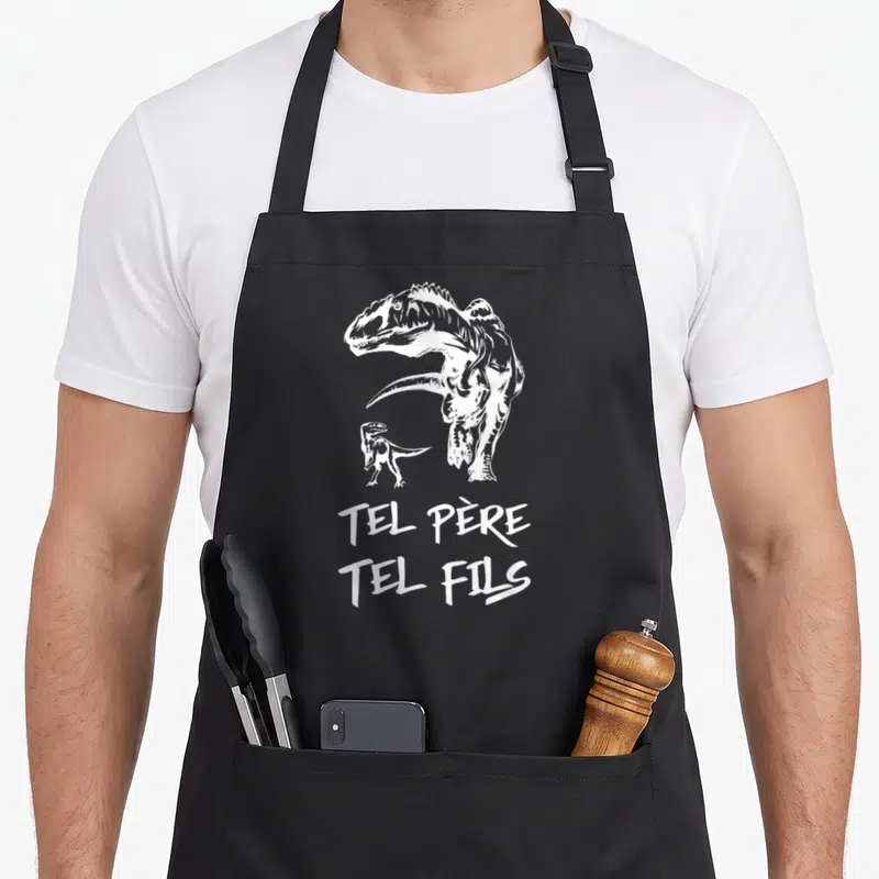 Tablier de cuisine noir avec illustration blanche d'un grand et d'un petit dinosaure sous le texte Tel Père Tel Fils.