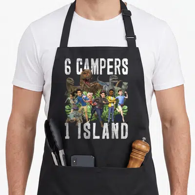 Tablier de cuisine noir avec illustration de six personnages animés et dinosaures sur fond de feuilles tropicales et texte blanc 6 Campers 1 Island.