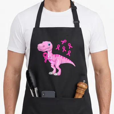 Tablier de cuisine noir avec illustration d'un dinosaure rose tenant un ruban et des symboles de sensibilisation.