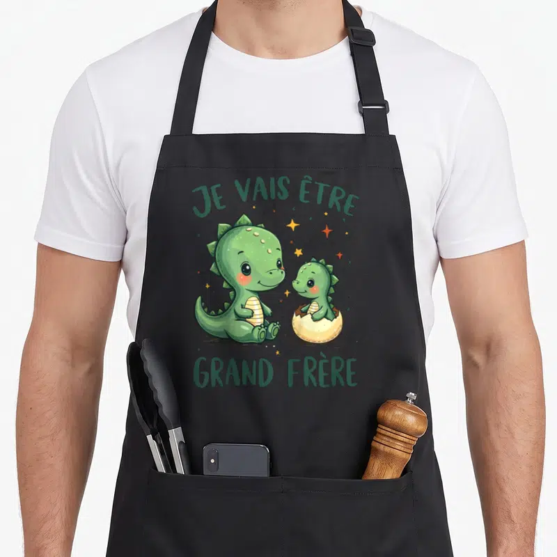 Tablier de cuisine noir avec illustration de deux dinosaures verts et texte Je vais être grand frère.