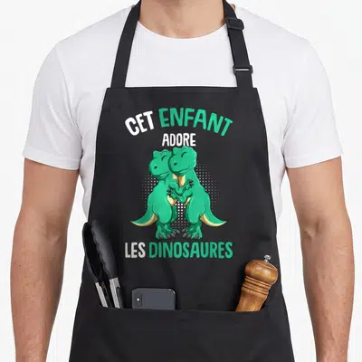 Tablier de cuisine noir avec deux dinosaures verts s'embrassant et le texte Cet Enfant Adore Les Dinosaures Garçons.