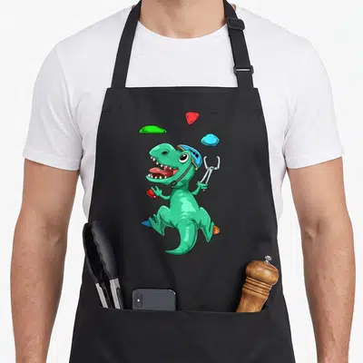Tablier de cuisine noir avec dinosaure vert en escalade portant un casque et tenant une pince.