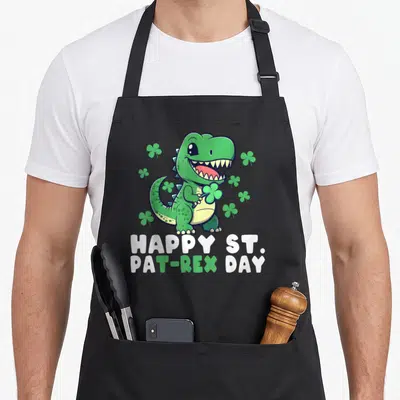 Tablier de cuisine noir avec un crocodile vert tenant un trèfle et le texte Happy St Pat-Rex Day