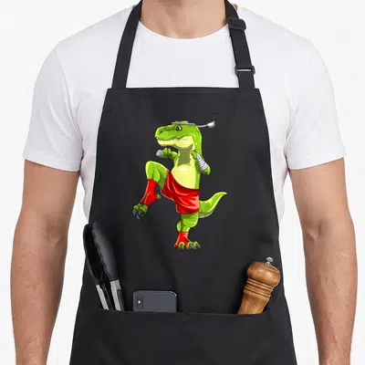 Tablier de cuisine noir avec illustration d'un T-Rex vert en position de boxe thaïlandaise, bandages blancs et short rouge.