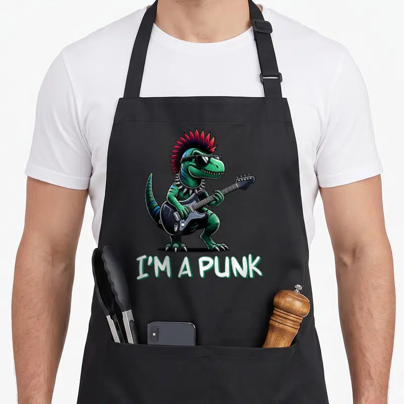 Tablier de cuisine noir avec un dinosaure vert punk aux cheveux roses jouant d'une guitare électrique noire et les mots I'm a Punk.