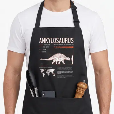 Tablier de cuisine noir avec illustration scientifique d'un Ankylosaurus, échelle humaine et données paléontologiques imprimées en blanc.