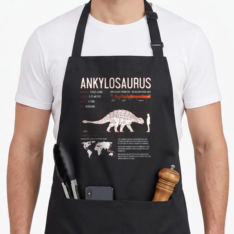 Tablier de cuisine noir avec illustration scientifique d'un Ankylosaurus, échelle humaine et données paléontologiques imprimées en blanc.