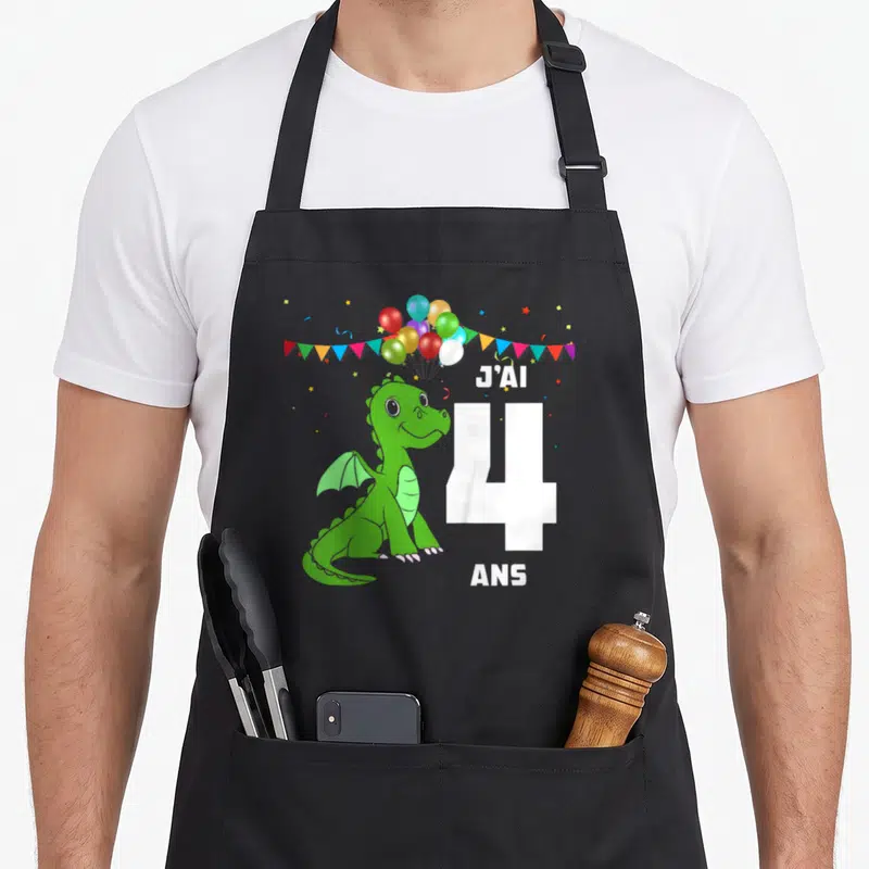 Tablier de cuisine noir avec dragon vert, ballons colorés et texte J'ai 4 ans imprimé au centre.