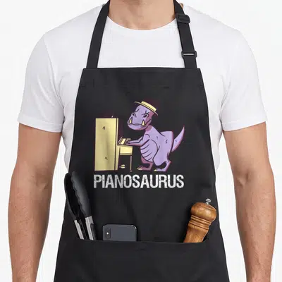 Tablier de cuisine noir avec illustration d'un dinosaure violet jouant du piano et le mot Pianosaurus