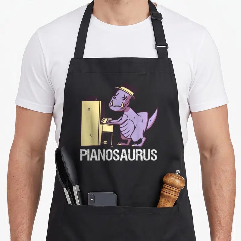 Tablier de cuisine noir avec illustration d'un dinosaure violet jouant du piano et le mot Pianosaurus