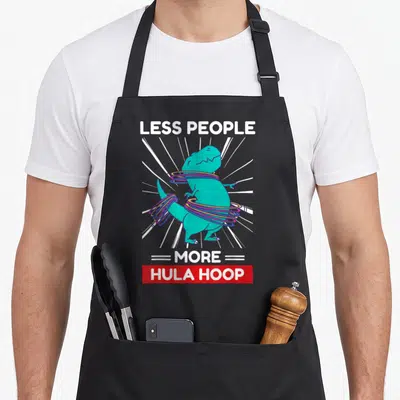 Tablier de cuisine noir avec un dinosaure turquoise utilisant des cerceaux colorés et le texte Less Gens Plus Hula Hoop.