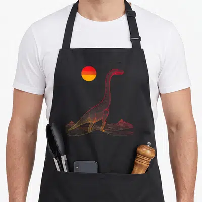 Tablier de cuisine noir avec illustration d'un Brontosaure aux traits rouges et oranges devant un soleil couchant stylisé.