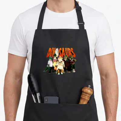 Tablier de cuisine noir avec une illustration colorée d'une famille de dinosaures en tenue vestimentaire.