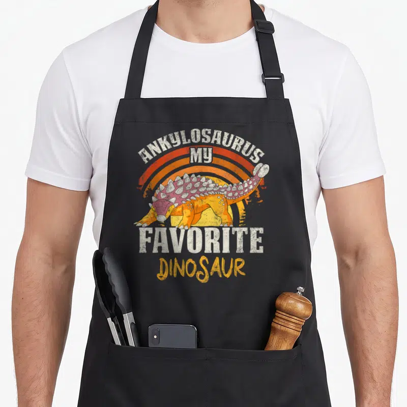 Tablier de cuisine noir avec illustration d'Ankylosaurus orange et texte My Favorite Dinosaur en style vintage.