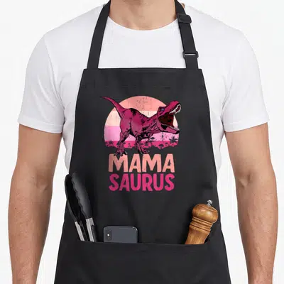 Tablier de cuisine noir avec illustration T-Rex rose et texte Mama Saurus en lettres capitales.