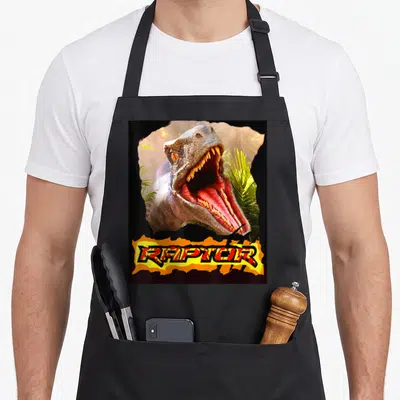 Tablier de cuisine noir avec illustration d'un Raptor Velociraptor aux dents acérées et l'inscription RAPTOR en style graffiti.