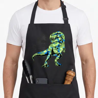Tablier de cuisine noir avec un T-Rex vert et bleu en motif camouflage devant un logo circulaire gris.