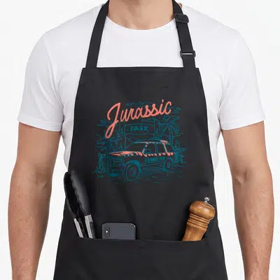 Tablier de cuisine noir avec illustration d'une jeep et d'une enseigne Jurassic Park en dessin au trait coloré.